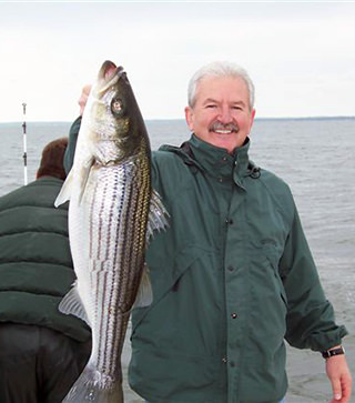 Natural Light Charter Fishing customer holding large Rockfish caught during a Chesapeake Bay charter fishing trip.